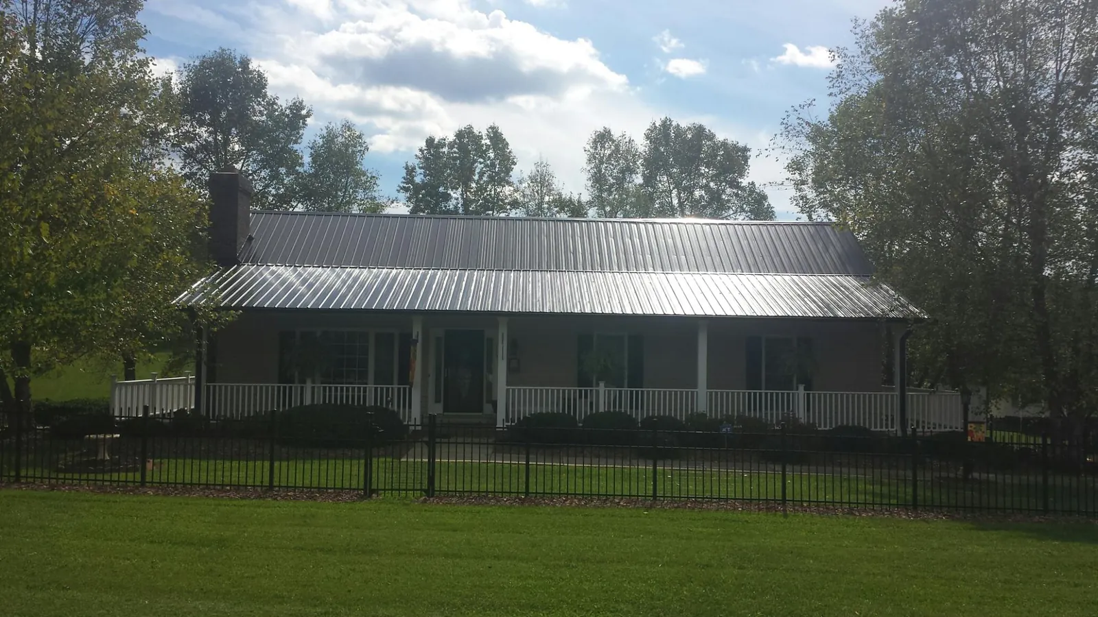 Gray metal roof on a brick ranch with a full width front porch — Gutter Guard Installation work by our crew in Belgrade