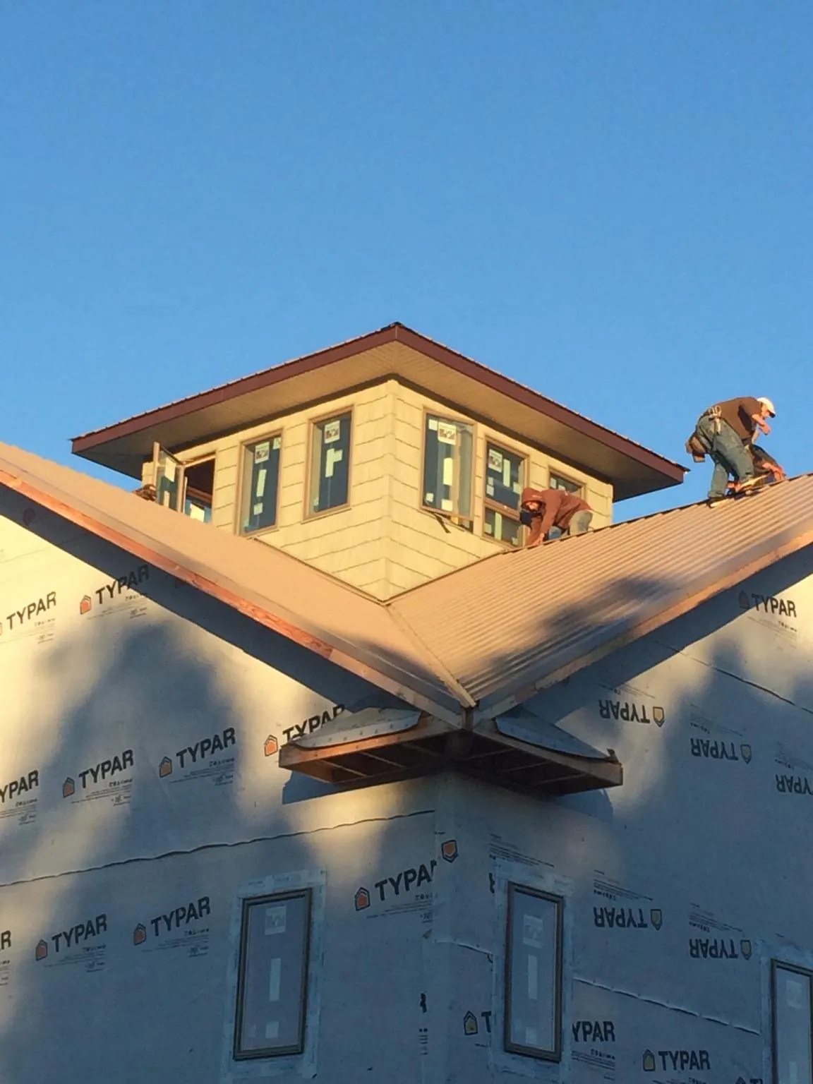 Roofers working around a rooftop cupola on a new metal roof at sunset — Roof Waterproofing in Belgrade by Roofing Brothers